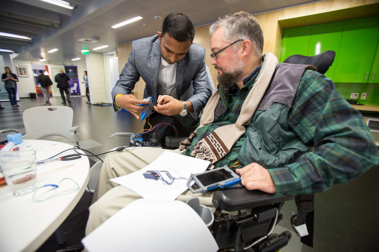 Gaurav Mukherjee helping Eric Rea put on NEO-Grasp, a neural-engineered orthosis at the CSNE's/UW's Neural Tech Studio presentations